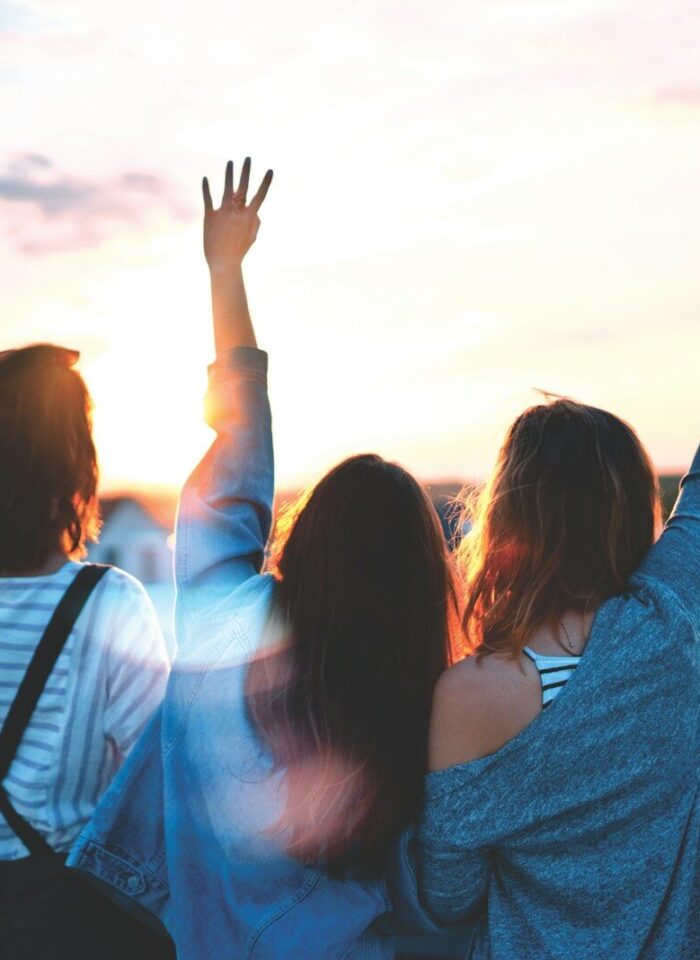 photo of three women lifting there hands